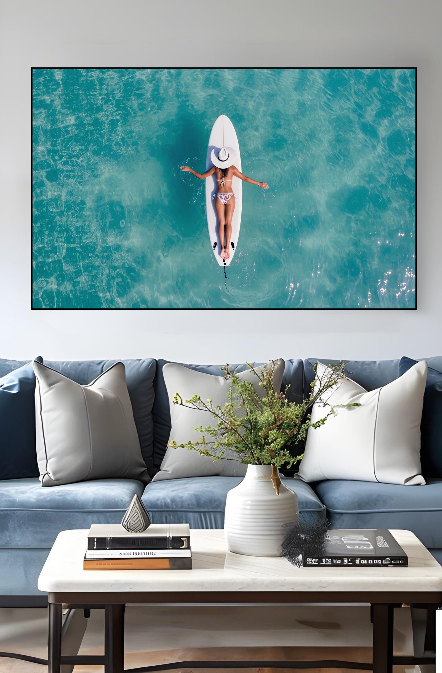Surfboard Woman Aerial Ocean Print – Minimalist Beach Wall Art decor above a couch, featuring a serene turquoise water scene.