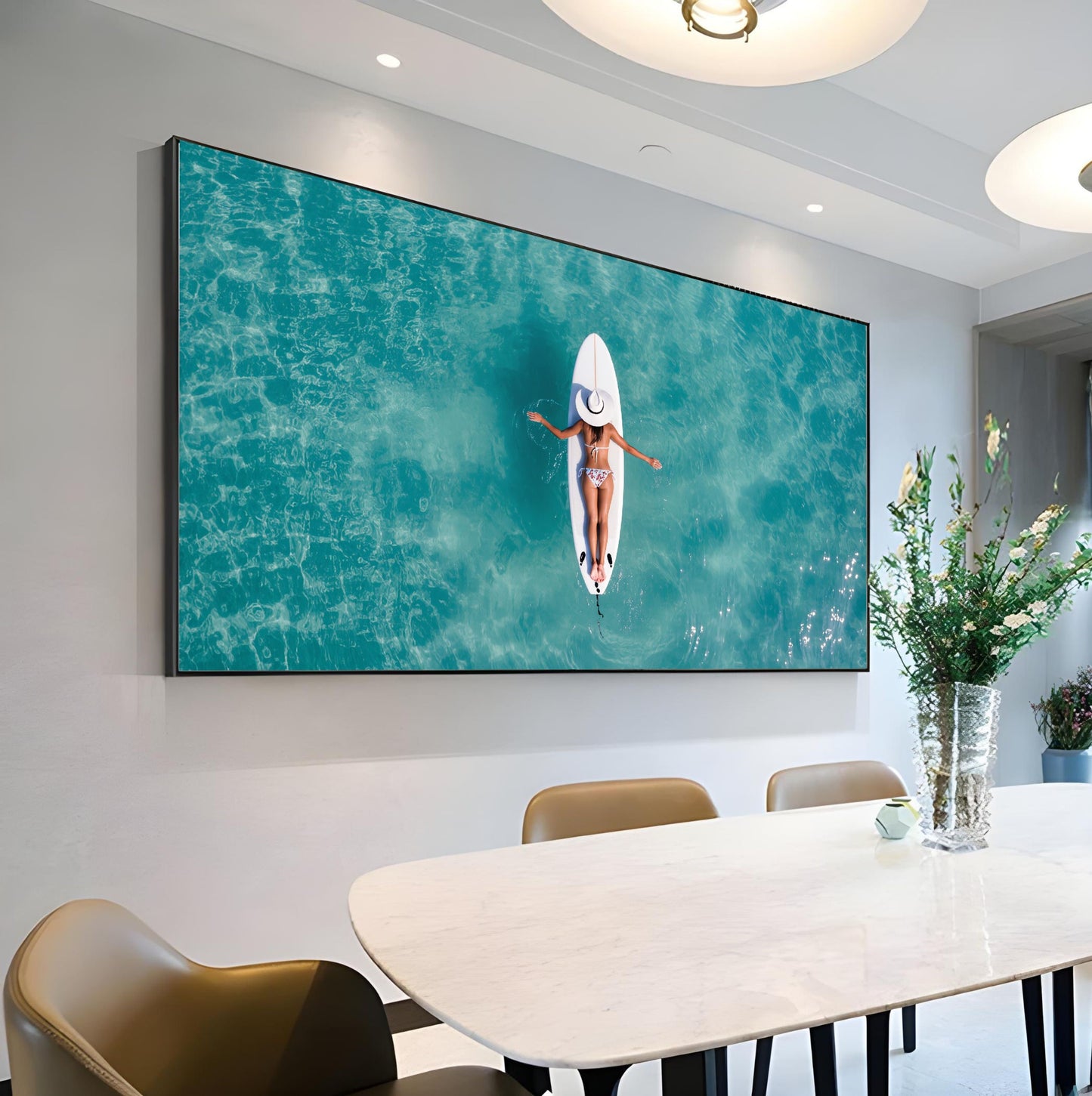 Surfboard Woman Aerial Ocean Print – Minimalist Beach Wall Art hanging in modern dining room, featuring woman on surfboard in turquoise sea.