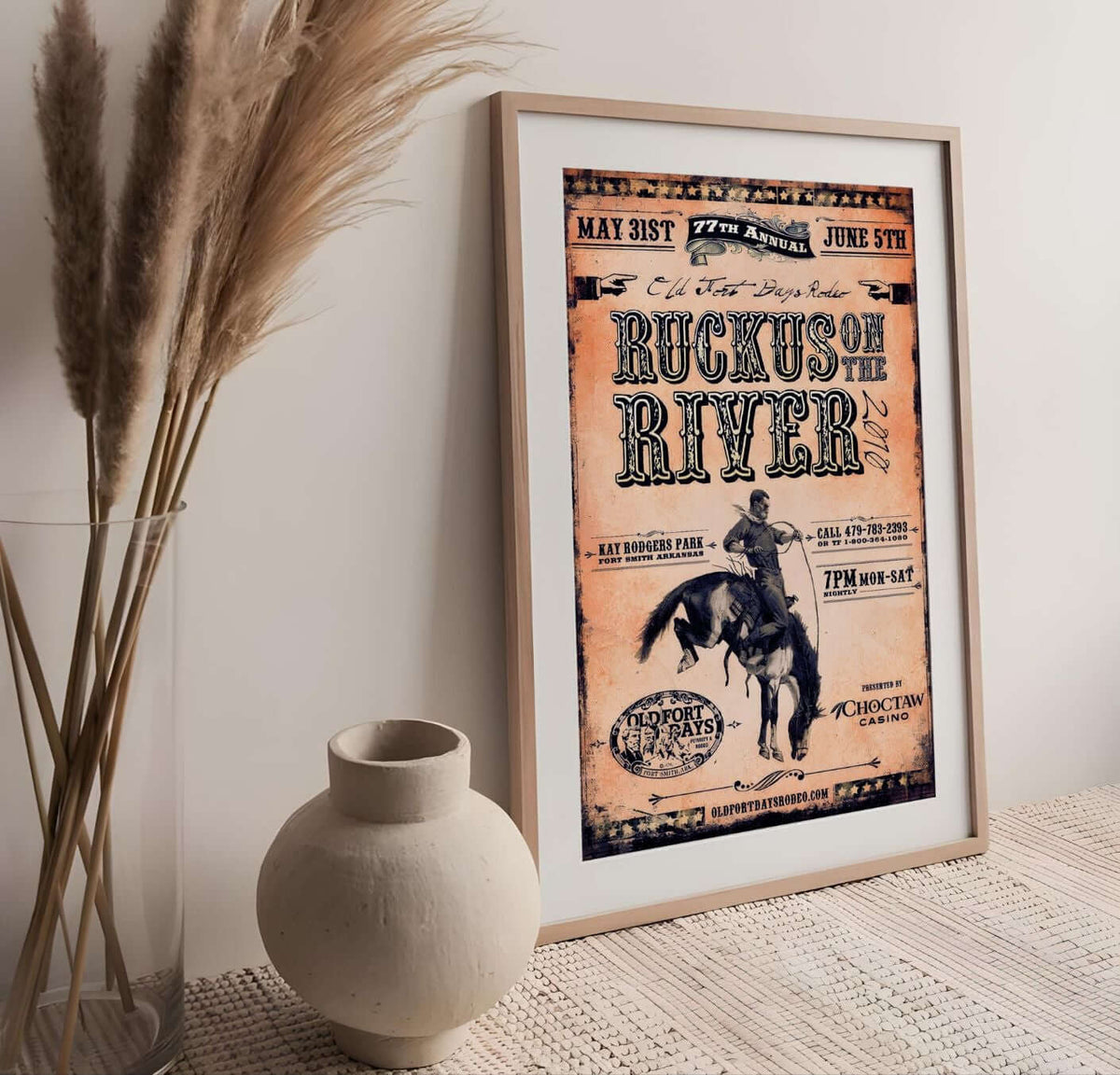 Ruckus on the River Rodeo Poster framed on a wall, showcasing vintage rodeo art and typography in a rustic setting.