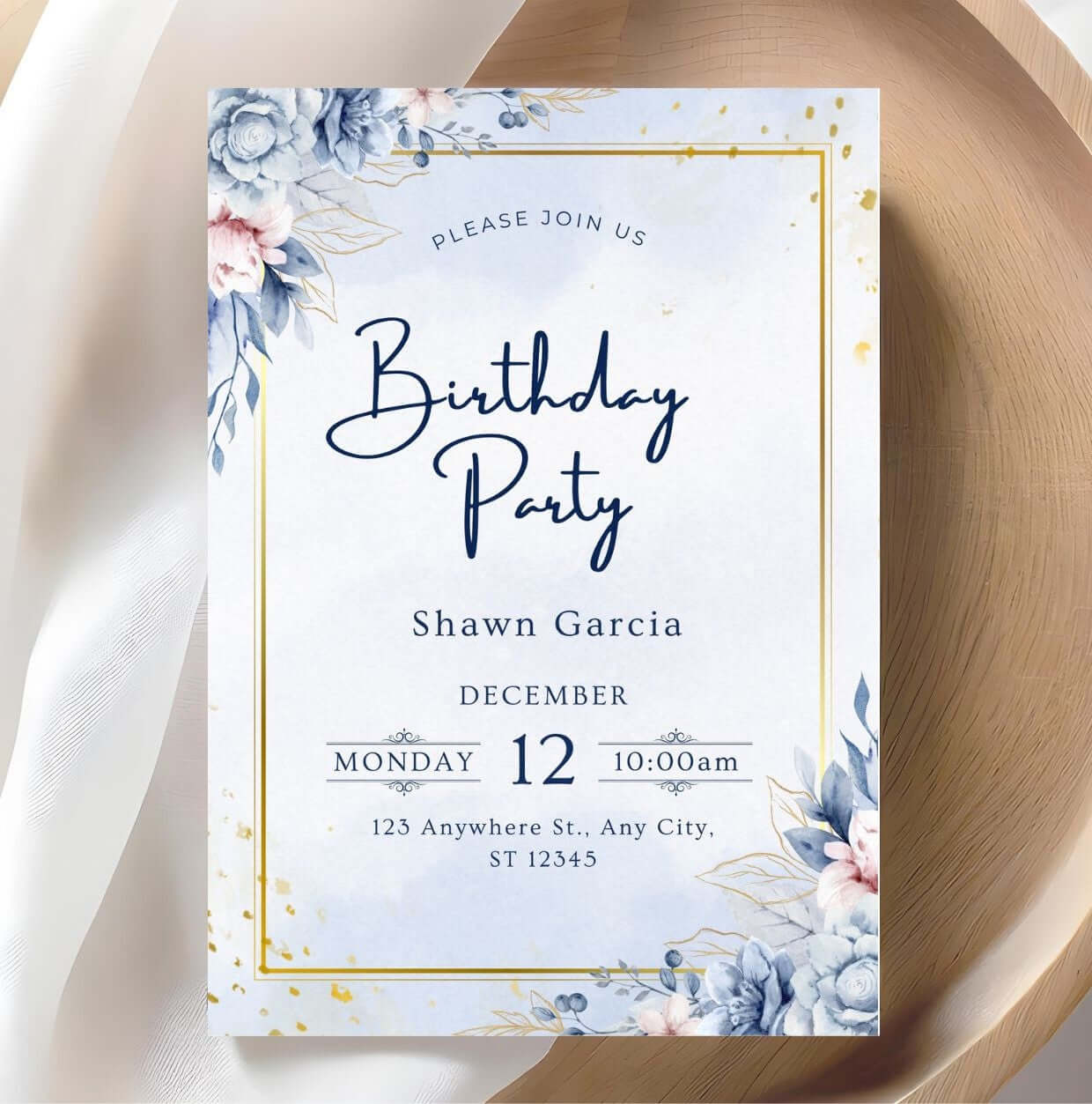 blue and gold birthday invitation with floral watercolor design on a wooden background