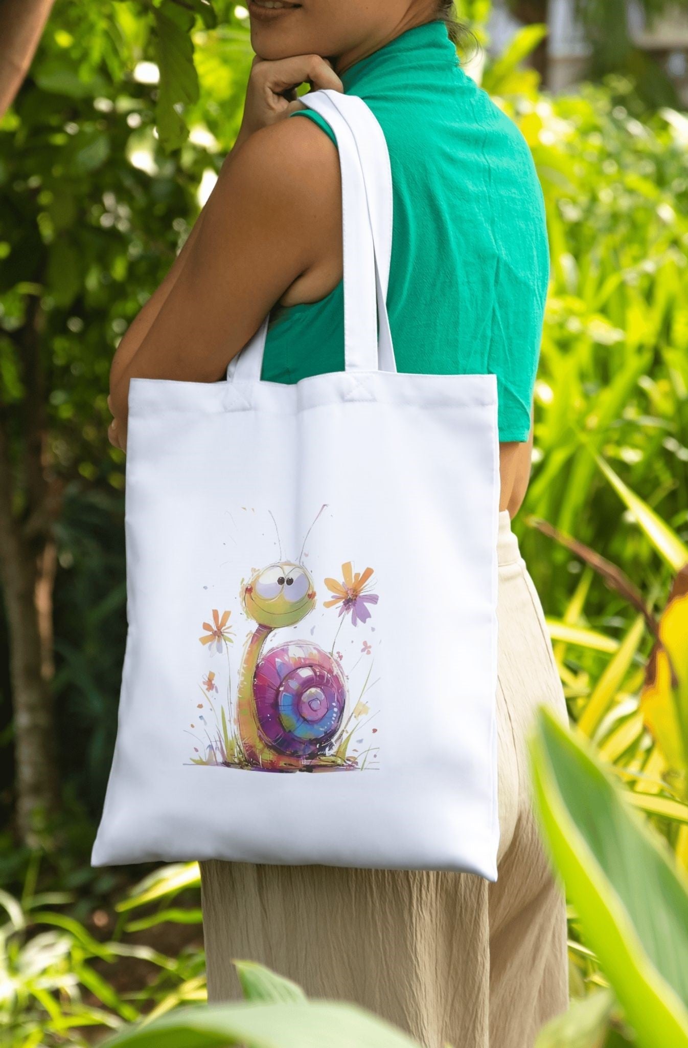 Person holding a tote bag featuring Cute Snail T-Shirt Design – Whimsical Colorful Snail Graphic in a garden setting.