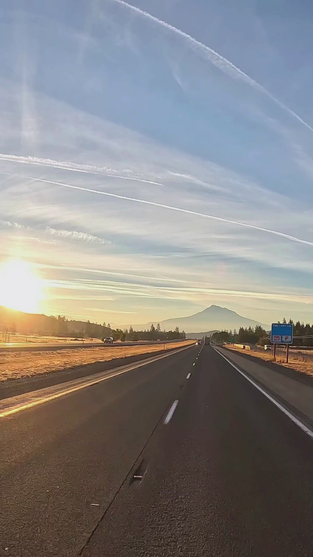 Empty highway during sunrise with mountain in the distance and clear blue sky