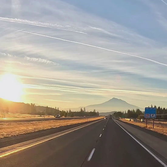 Scenic highway at sunrise with mountain view and clear sky.